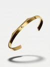Gold bracelet on a light gray background