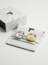 Two rings, one silver and one gold, on a white card with text in a branded box.