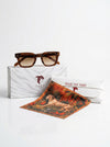 Sunglasses and a patterned scarf with T.U.C.C. branding on a white background