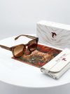 Sunglasses with a box and tiger-themed paper on a white surface