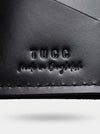 Close-up of a black leather product with 'TUCC made in Bangladesh' embossed on it.
