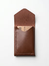 Brown leather pouch with a brand label on a white background