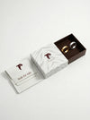 Two rings in a branded box with a card on a white background